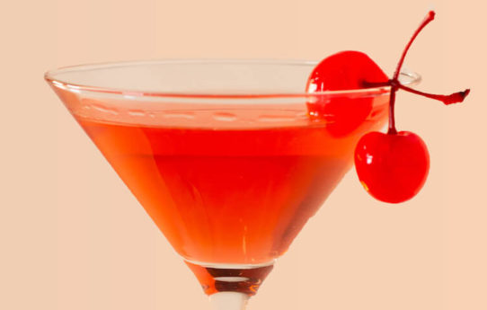 Red cocktail in a martini glass with maraschino cherries on the rim.