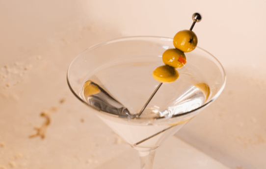 A martini with olives sticking out of it.